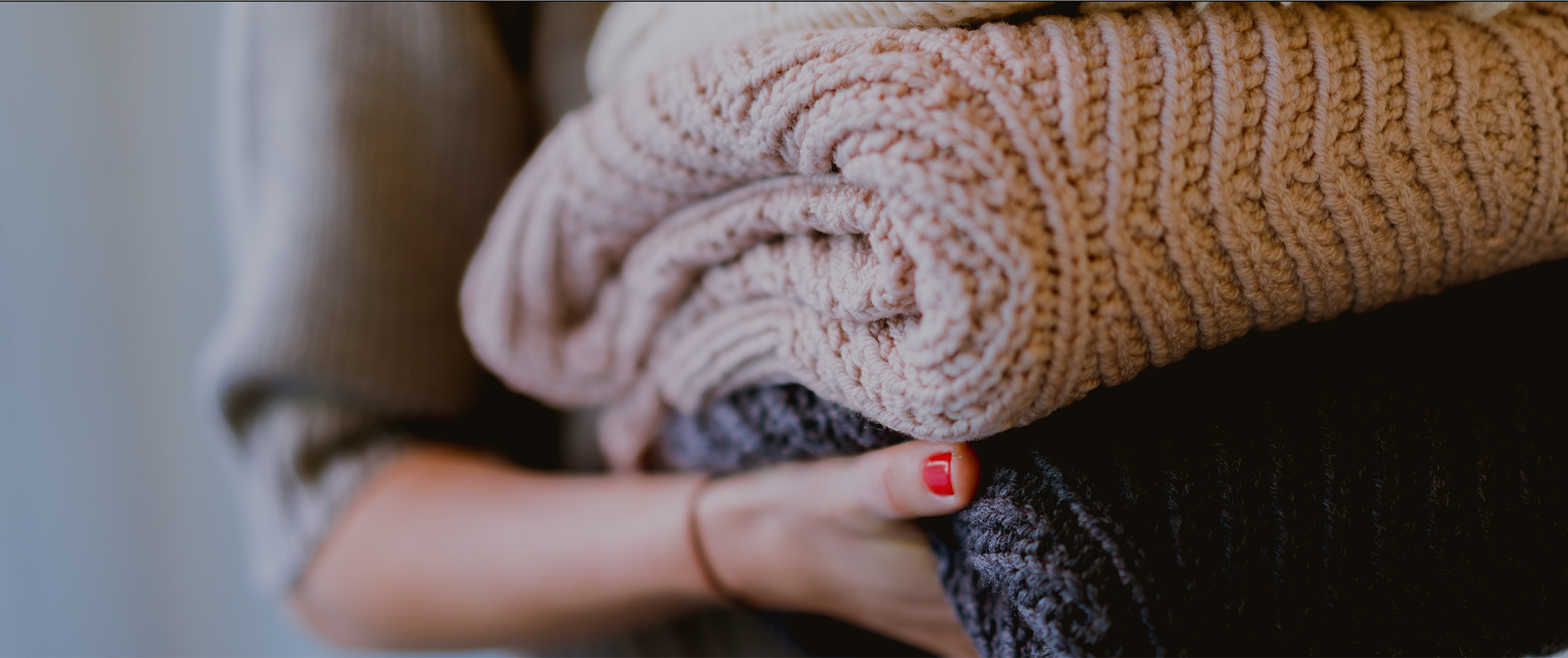 Female arms holding folded sweaters